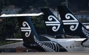 Air New Zealand airplanes wait for passengers outside the international terminal as a plane taxis (L) at Wellington International airport on February 20, 2020.