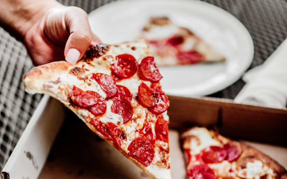 a person's hand holding a slice of pizza