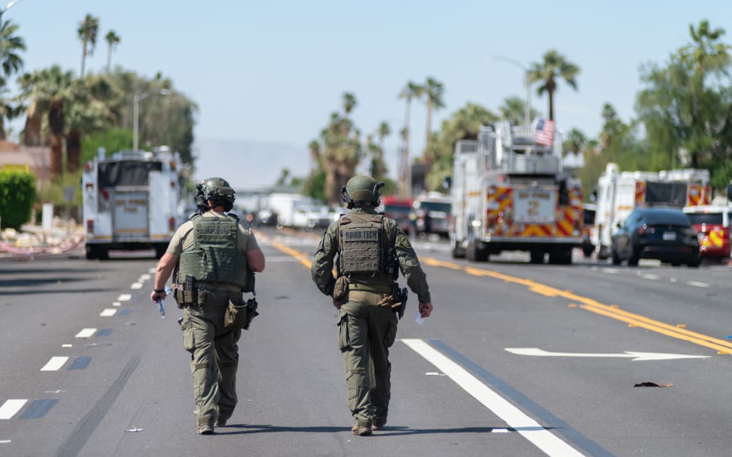 Two bomb squad officers walk near near the scene of a bomb blast which damaged a fertility clinic and left one person dead, May 17, 2025 in Palm Springs, California. A bomb blast outside a California fertility clinic killed one person Saturday, in what the US attorney general called an "unforgivable" attack. The blast ripped through downtown Palm Springs, badly damaging the clinic and blowing out the windows and doors of other nearby buildings. (Photo by Gabriel Osorio / AFP)