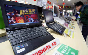 A customer shops for Toshiba laptop computers at a home appliance store in Nantong city, east China's Jiangsu province, 28 January 2011.