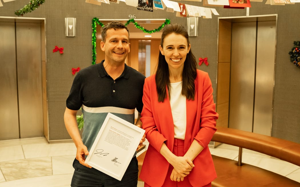 David Seymour and Jacinda Ardern with the signed transcript of her calling him an "arrogant prick" in Parliament. They plan to auction it off to charity.
