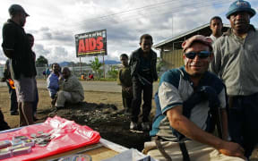 Residents sell their goods near a anti-Aids billboard in Mount Hagen, 18 August 2007.