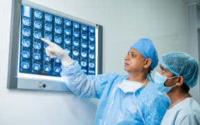 doctors in operation gown analysing x report before performing operation at hospital - concept of medical expertise, examining and medical care.