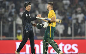 South Africa's captain Aiden Markram (R) is congratulated by his New Zealand counterpart Mitchell Santner for his team's win at the end of the 2026 ICC Men's T20 Cricket World Cup group stage match between New Zealand and South Africa in the Narendra Modi Stadium, Ahmedabad on February 14, 2026. (Photo by Shammi MEHRA / AFP)