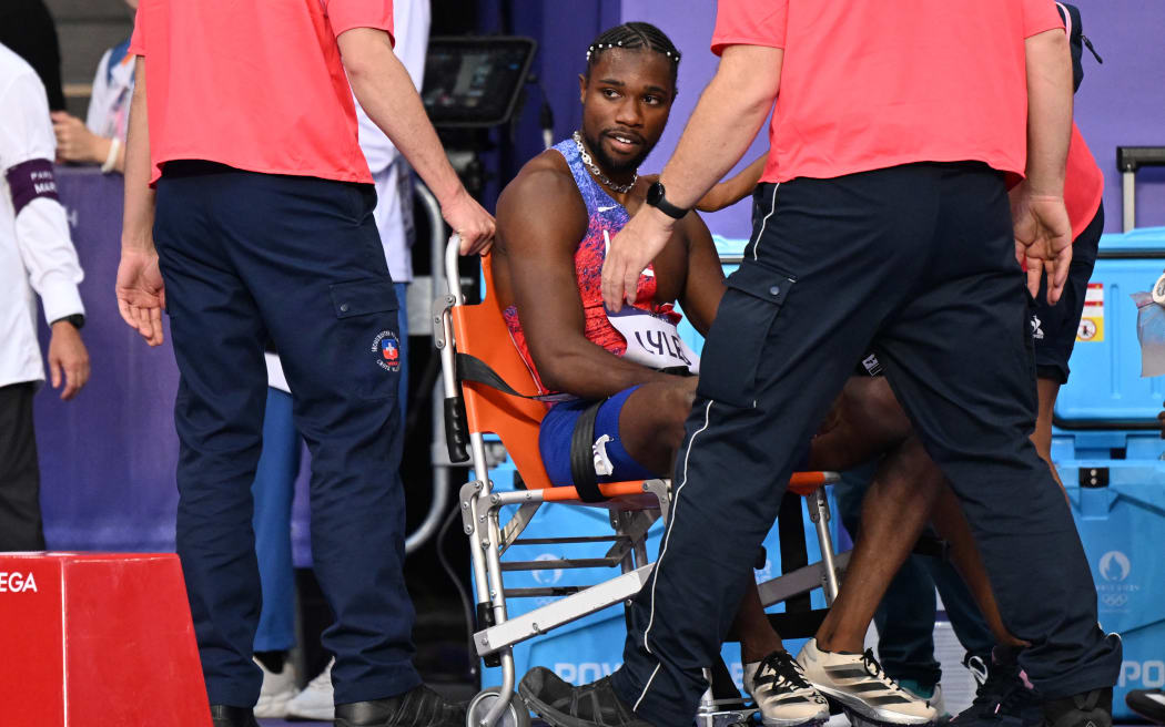 Bronze medallist US' Noah Lyles (C) receives medical attention after competing in the men's 200m final of the athletics event at the Paris 2024 Olympic Games at Stade de France in Saint-Denis, north of Paris, on August 8, 2024. (Photo by Kirill KUDRYAVTSEV / AFP)