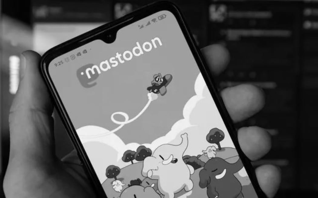 A hand holding a phone showing Mastodon