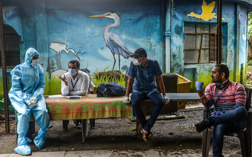 Health workers and civic staff wait for students at the Children Aid Society premises during a medical screening for the COVID-19 coronavirus, in Mumbai on July 29, 2020.
