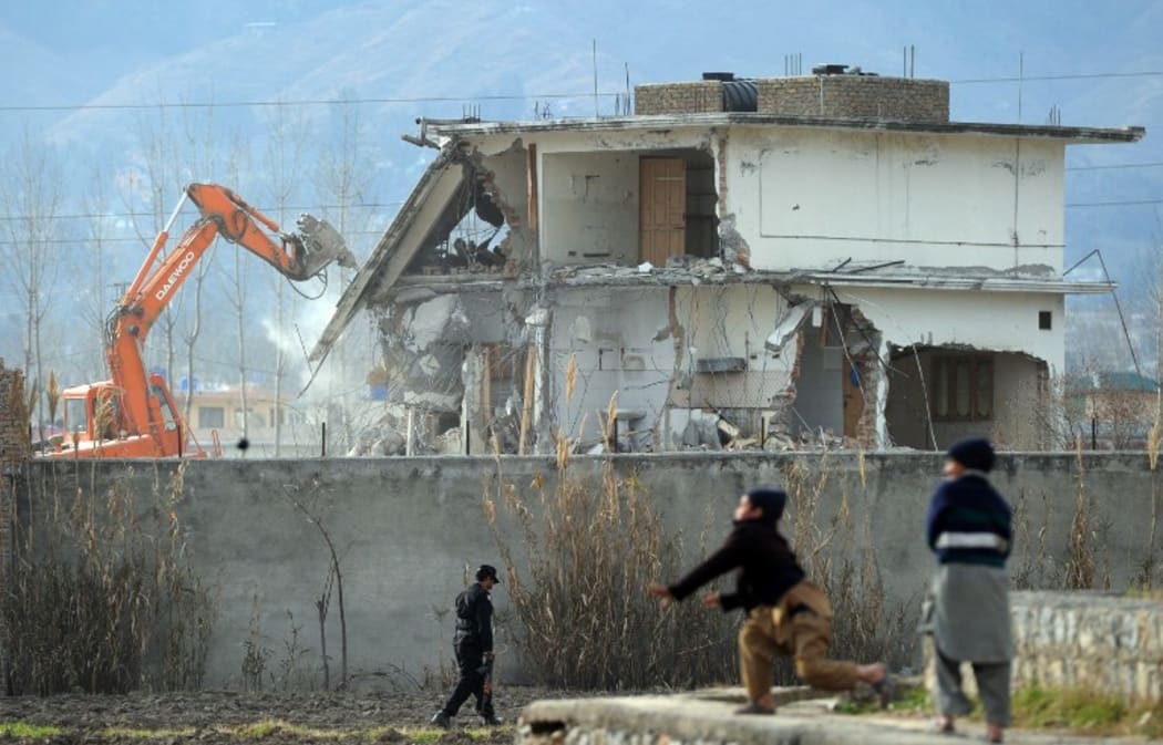 Young Pakistani boys play near demolition works on the compound where Al-Qaeda chief Osama bin Laden was slain.