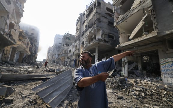 A Palestinian man points at destruction as people inspect the damage following overnight Israeli airstrikes in the Gaza Strip's Jabalia refugee camp on October 11, 2023, amid continuing battles between Israel and the Hamas movement. The death toll from five days of ferocious fighting between Hamas and Israel rose sharply overnight as Israel kept up its bombardment of Gaza after recovering the dead from the last communities near the border where Palestinian militants had been holed up. (Photo by Mahmud HAMS / AFP)