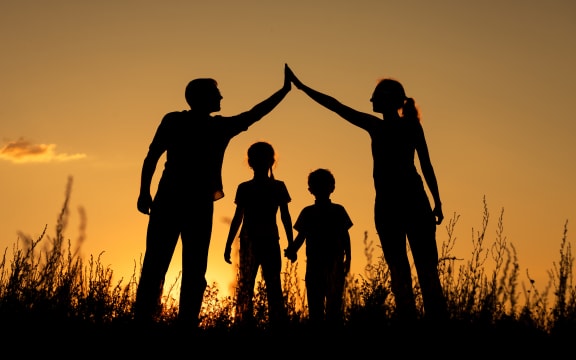 Happy family standing in the park at the sunset time.  Concept of friendly family.