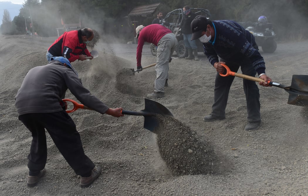 Local residents remove ashes from a street in La Ensenada after last week's eruption.