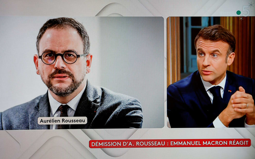 A television screen broadcasting French TV channel France 5 as a picture of French Health Minister Aurelien Rousseau (left), who resigned, is seen during an interview of French President Emmanuel Macron in the "C a vous" TV show, following the approval of the law to control immigration, on 20 December, 2023.