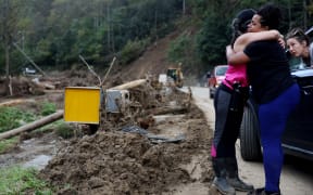 BLACK MOUNTAIN, NORTH CAROLINA - OCTOBER 03: Tammie Mance hugs her boss Liesl Steiner (L), whose home was destroyed, after seeing each other for the first time since the storm in the aftermath of Hurricane Helene flooding on October 3, 2024 in Black Mountain, North Carolina. At least 200 people were killed in six states in the wake of the powerful hurricane which made landfall as a Category 4. President Joe Biden took an aerial tour of the devastated region yesterday and ordered the deployment of 1,000 active duty U.S. soldiers to assist with storm relief efforts and reinforce the North Carolina National Guard.   Mario Tama/Getty Images/AFP (Photo by MARIO TAMA / GETTY IMAGES NORTH AMERICA / Getty Images via AFP)