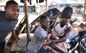 A wounded man takes shelter in a market stall in Harare as protests turned violent.