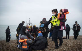 A member of the UK Border Force helps child migrants on a beach in Dungeness, on the south-east coast of England, on November 24, 2021 after being rescued while crossing the English Channel.