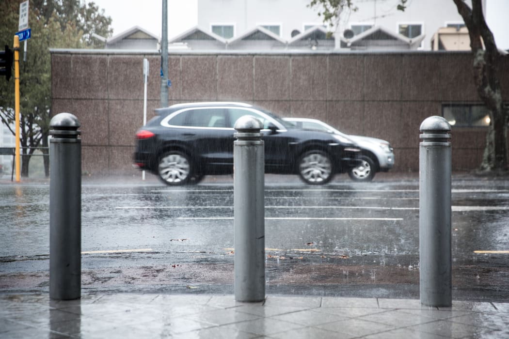 Rain pours down as cars drive by.