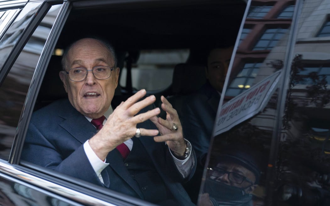 Rudy Giuliani talks to reporters as he leaves after his defamation trial in Washington, on 15 December, 2023.