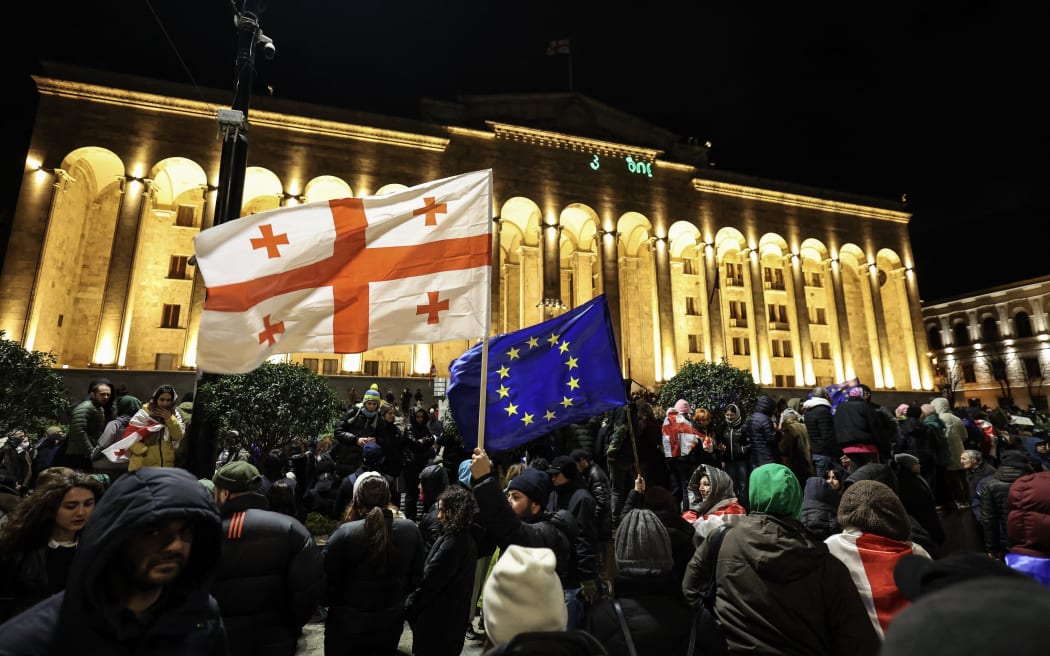 Demonstrators with the flag of Georgia (L) and the European Union gather to protest in front of Georgia's parliament in downtown Tbilisi on November 28, 2024, after Prime Minister Irakli Kobakhidze said the country would not pursue European Union accession until 2028, accusing Brussels of "blackmail". - The announcement came hours after the European Parliament adopted a non-binding resolution rejecting the results of Georgia's October 26 parliamentary elections, alleging "significant irregularities". (Photo by Giorgi ARJEVANIDZE / AFP)