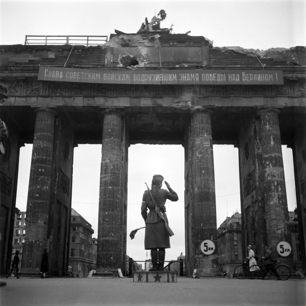 A Soviet Red army woman soldier controls traffic in front of the Brandenburg Gate, in July 1945 in Berlin.