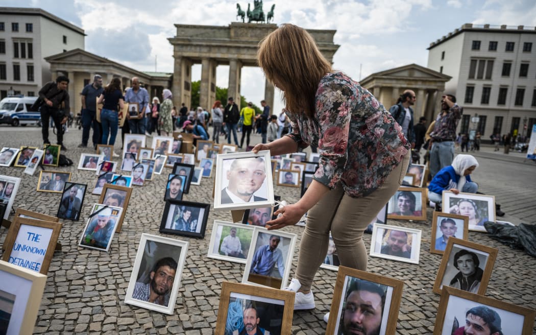 Activists and relatives of Syrians suspected of being detained or missing pose with their portraits during a demonstration in front of Berlin's Brandenburg gate on 7 May, 2022.