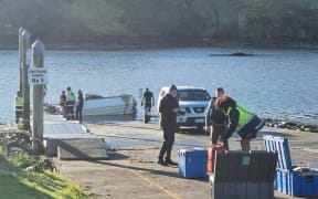 Investigators at the scene as the a boat that capzized off the coast of South Taranaki is retrieved.