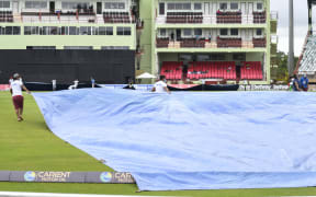 Ground staff pull on the covers as rain stopped play at Guyana National Stadium in Providence, Guyana, 2021.