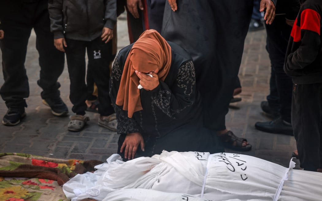 A woman mourns over the shrouded bodies of loved ones, killed in Rafah during Israeli bombardment on the southern Gaza strip, at Al-Najar hospital on December 29, 2023, amid continuing battles between Israel and the Palestinian militant group Hamas. (Photo by AFP)