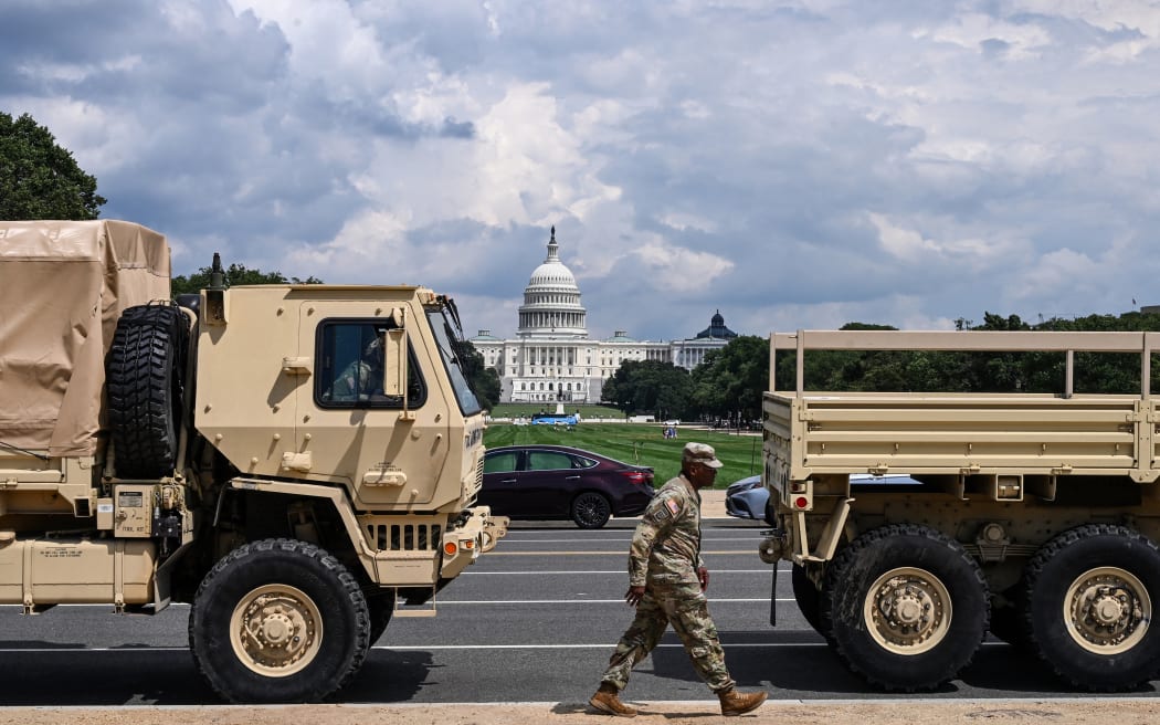 A member of the US National Guard walks past military vehicles on the National Mall in Washington, DC, on August 14, 2025. US President Donald Trump on August 11 deployed military and federal law enforcement to curb violent crime in Washington, as he seeks to make good on his campaign pledge to be a "law and order" president. The Republican leader said he would place the city's Metropolitan Police under federal government control while also sending the National Guard onto the streets of the US capital. (Photo by Alex WROBLEWSKI / AFP)