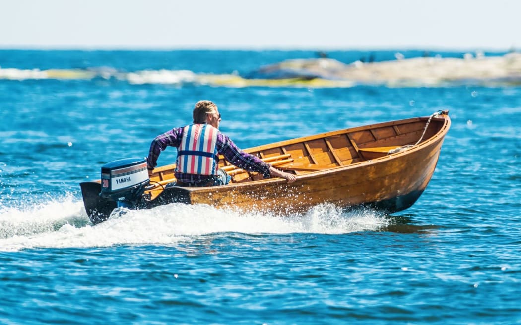man driving motorboat, lifejacket