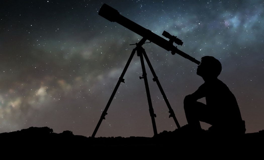 Artwork of a boy looking through a telescope, seen in silhouette against the star clouds of the Milky Way. The boy is using a refracting telescope. (Photo by MARK GARLICK/SCIENCE PHOTO LIBRA / MGA / Science Photo Library via AFP)