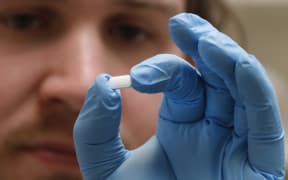 A pharmacy tech holds a pill of Hydroxychloroquine in Utah, on 20 May.