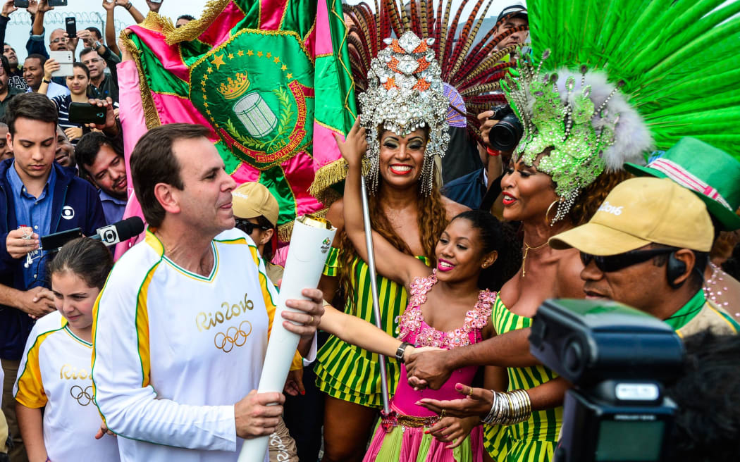 The mayor of Rio de Janeiro, Eduardo Paes carries the Olympic torch on its arrival in the city on 3 August.