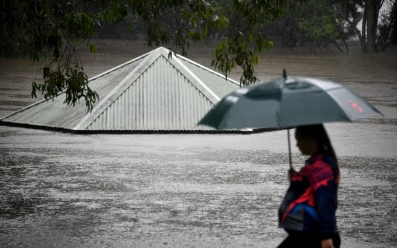 A woman walks past a flooded park along the overflowing Nepean river in Penrith on 21 March as Sydney braced for its worst flooding in decades.