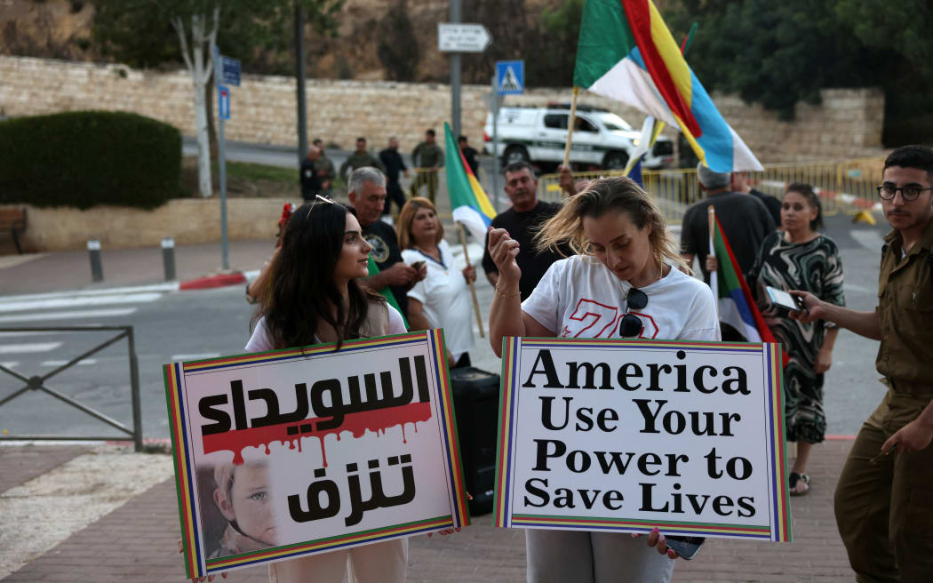 Members of the Druze community in Israel and their supporters wave a Druze flag and raise placards near the US Embassy in Jerusalem to show solidarity with their community in neighbouring Syria, on July 16, 2025. The clashes began on July 13 between the Druze and Bedouin tribes in soutern Syria's Sweida city, who have a long-running feud, sparking an intervention by government forces. (Photo by AHMAD GHARABLI / AFP)