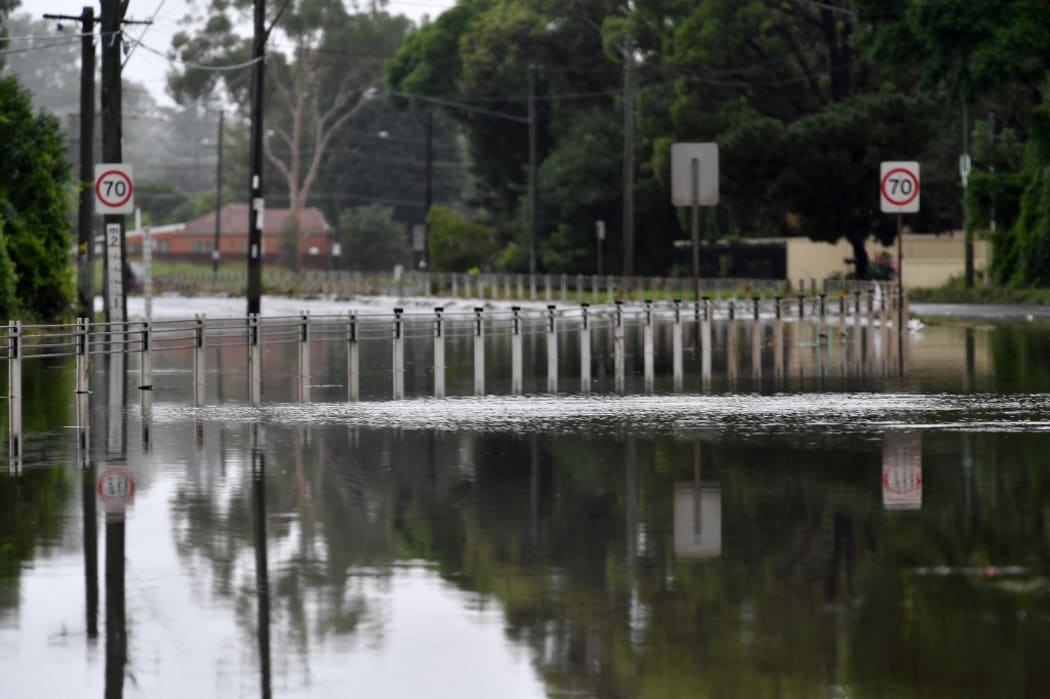 A main road is blocked by flood waters on the bank of Georges river on March 3, 2022, as Sydney faces its worst flooding after record rainfall caused its largest dam to overflow