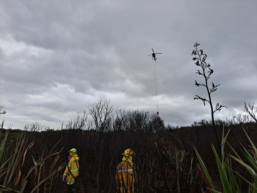 A helicopter supporting ground crews to extinguish hotspots at the Tiwai Road fire in Awarua this morning.