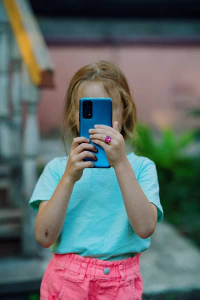 A young girl looks at the screen of a smartphone.