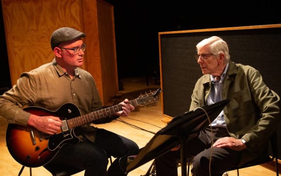 Guitarist Dixon Nacey holding a guitar and talking to Kevin Haines
