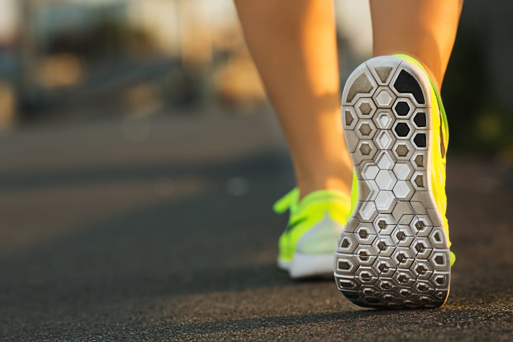 Woman runner showing feet and running shoes on track or road.