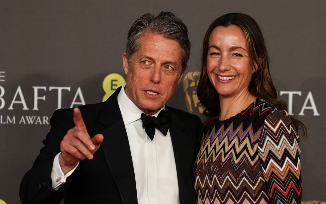 British actor Hugh Grant (L) and his wife Anna Elisabet Eberstein pose on the red carpet upon arrival at the BAFTA British Academy Film Awards at the Royal Festival Hall, Southbank Centre, in London, on February 18, 2024. (Photo by Adrian DENNIS / AFP)