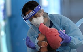 A health worker collects swab samples from a resident at a Covid-19 testing clinic in Sydney on July 17, 2021. (Photo by Steven SAPHORE / AFP)