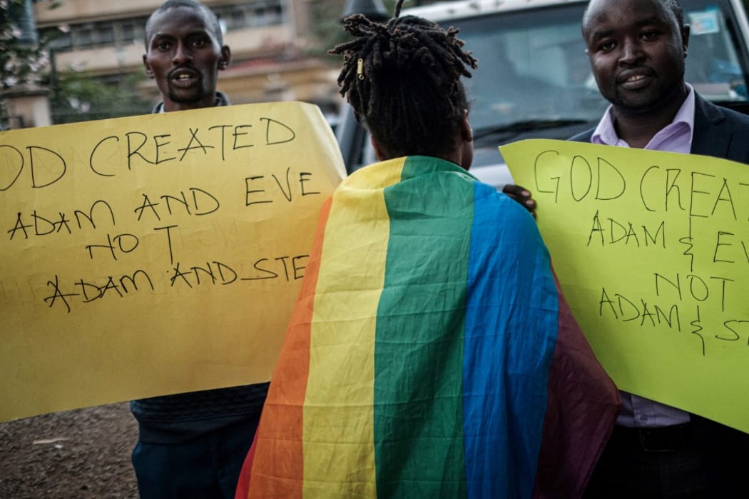 A woman wearing a rainbow flag walks between Christian members of the Sozo church of God as they hold anti-LGBTQ signs and sing against homosexuality after a verdict on scrapping laws criminalising homosexuality in front of the Milimani high court in Nairobi, Kenya.