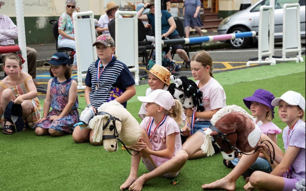 A group of children sitting with their hobby horses at the Whanganui hobby horse competition