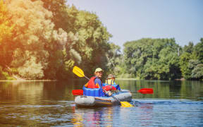 A photo of a happy Kid kayaking with his sister on the river. Active girl having fun enjoying adventurous experience with kayak on a sunny day during summer vacation