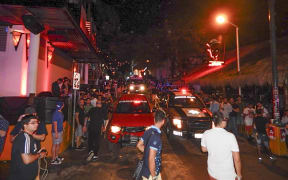 People remain in the street outside the Blue Parrot nightclub as firefighters and police agents patrol the area in Playa del Carmen, Quintana Roo state, Mexico where 5 people were killed, three of them foreigners, during a music festival on January 16, 2017.