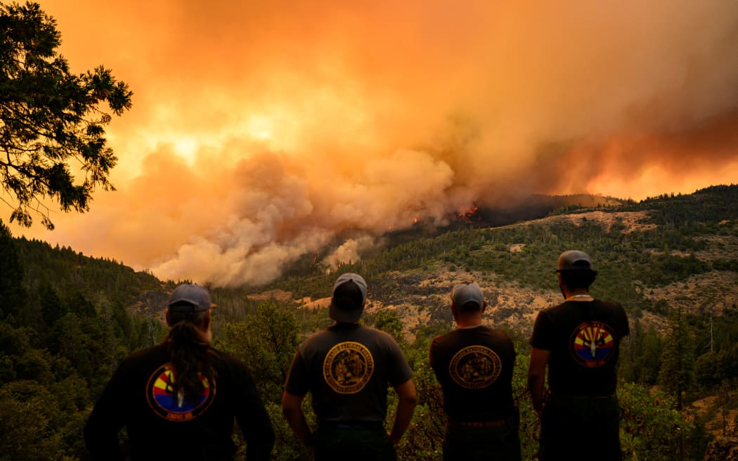 Firefighters watch as flames and smoke move through a valley in the Forest Ranch area of Butte County as the Park Fire continues to burn near Chico, California, on 26 July 2024.