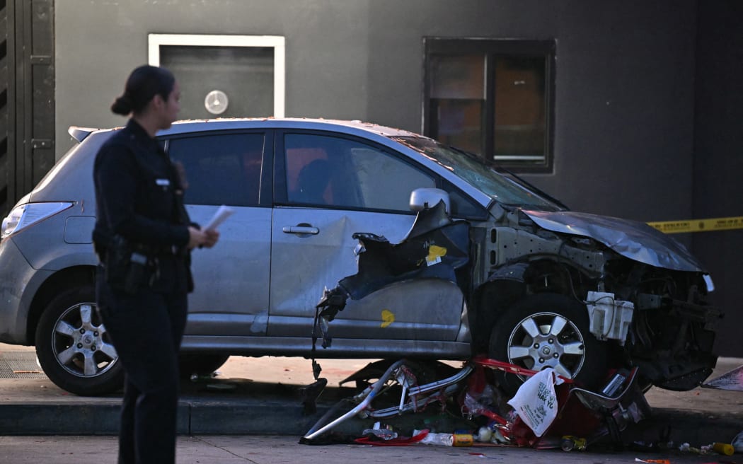 Officers stand at the scene of a crashed vehicle which drove into a crowd in Hollywood in the early hours of July 19, 2025, injuring 28 people, according to the Los Angeles Fire Department. More than 100 firefighters responded to the scene in East Hollywood assisting three patients in critical condition, six in serious condition and 19 listed as fair, the Fire Department said. (Photo by Robyn BECK / AFP)