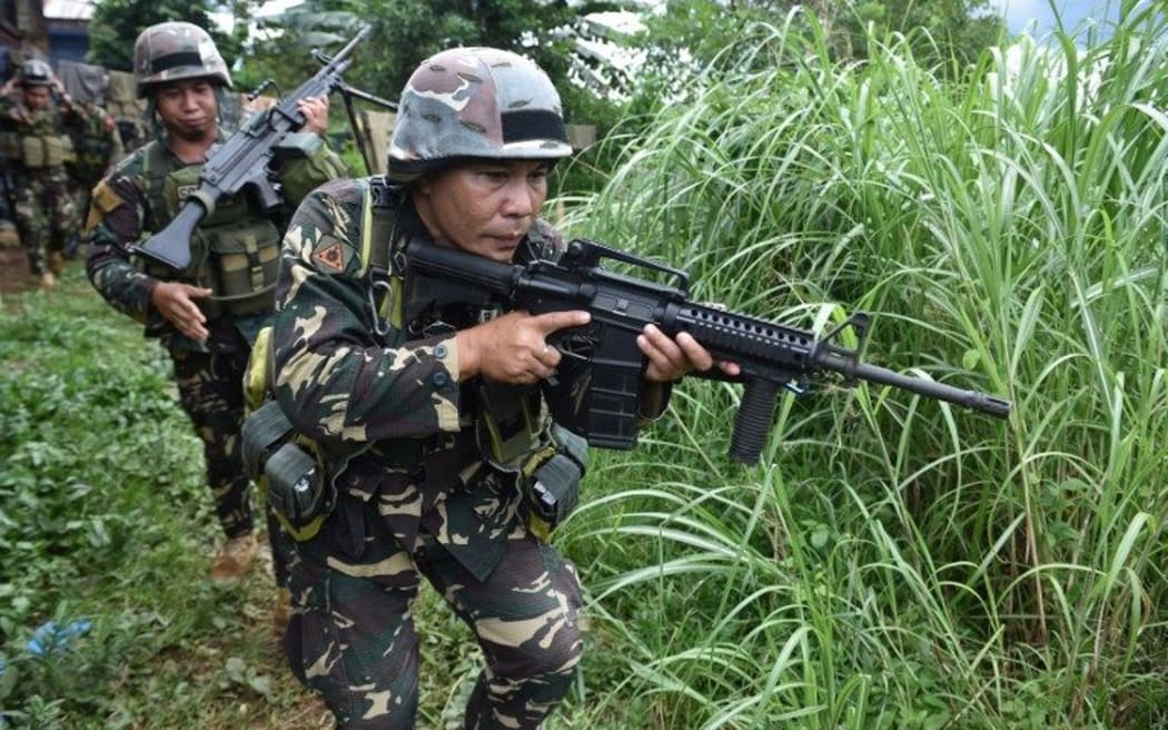 Philippine troops patrol a grassy area near the frontline in Marawi on the southern island of Mindanao on June 19, 2017, as the armed conflict between government troops and Islamist militants enters its fourth week.