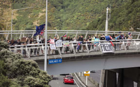 Protest convoy supporters hold signs at the Newlands Road interchange near Wellington.