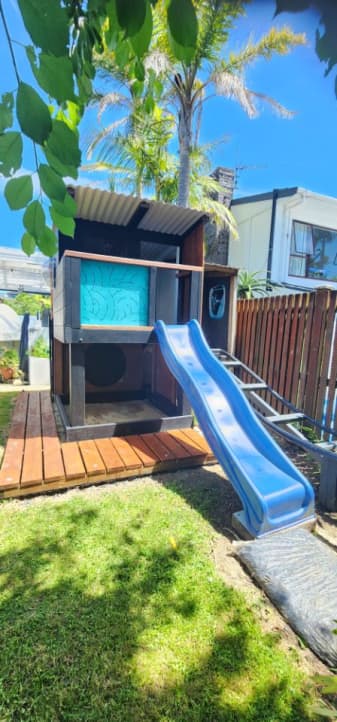 The playhouse has a plastic slide alongside the roller coaster track.